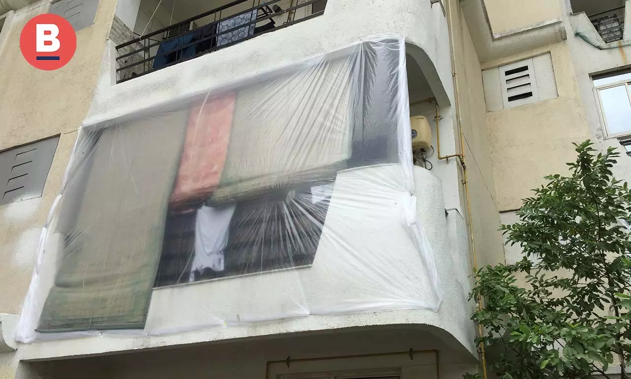 Residents of Emerald Court have covered their balconies with plastic sheets to avoid dust entering homes on Sunday. Photo by Kaisar Andrabi 
