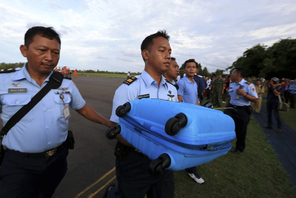 Air force personnel carry luggage presumed to be from missing Indonesia AirAsia flight QZ 8501 recovered from the sea at Pangkalan Bun (Credit: Reuters)