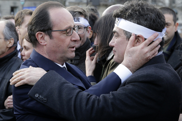 French President Francois Hollande comforts French columnist for Charlie Hebdo Patrick Pelloux as they take part in a solidarity march (Marche Republicaine) in the streets of Paris