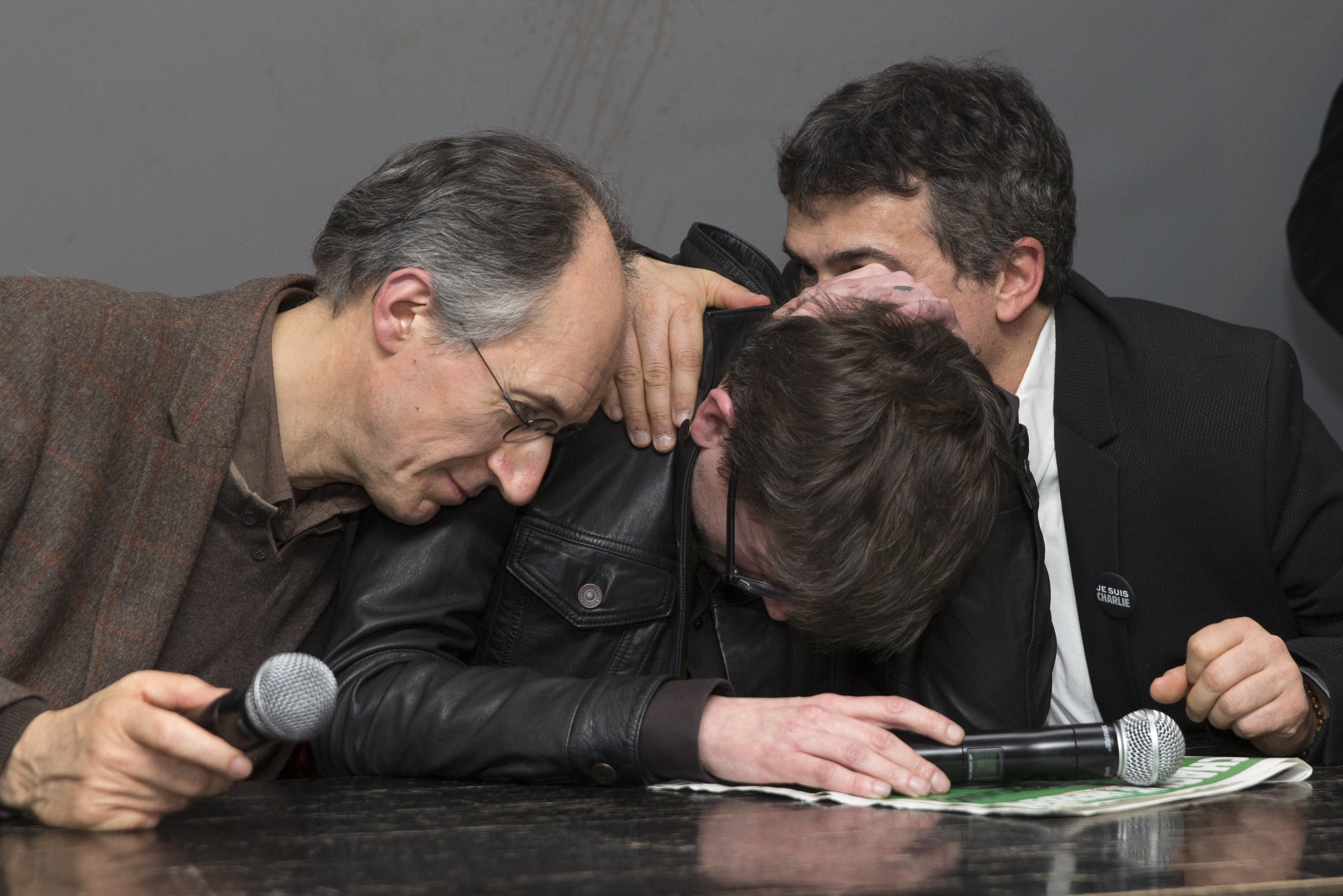 Satirical French magazine Charlie Hebdo new editor in chief Briard and columnist Pelloux comfort cartoonist Luz during a news conference at the French newspaper Liberation offices