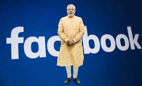 Image shows Modi standing before Fb logo